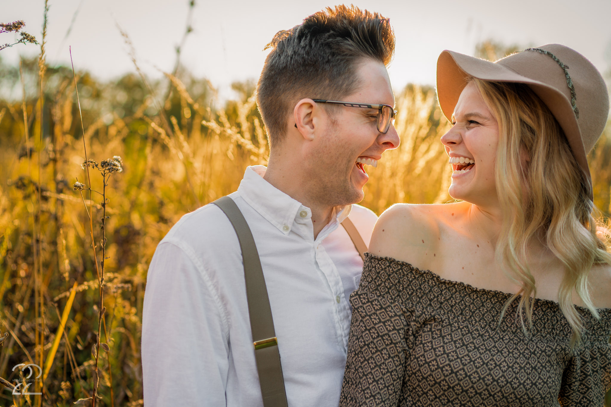 Man and woman laugh together in a field during sunset at Wegerzyn Garden Metropark by Dayton Wedding Photographer Studio 22 Photography